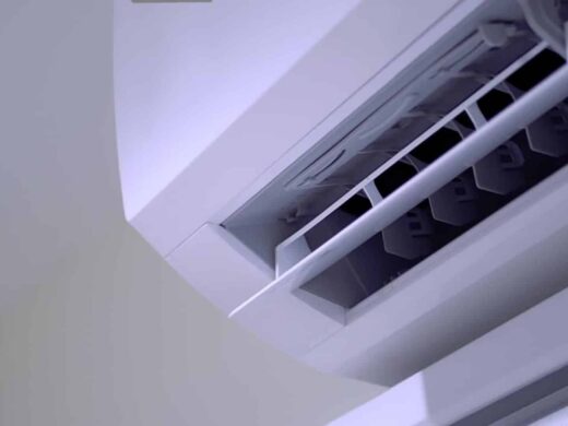 Détail d'une unité de climatisation murale blanche, centrée sur le ventilateur et les commandes.