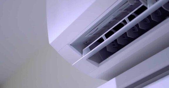 Détail d'une unité de climatisation murale blanche, centrée sur le ventilateur et les commandes.
